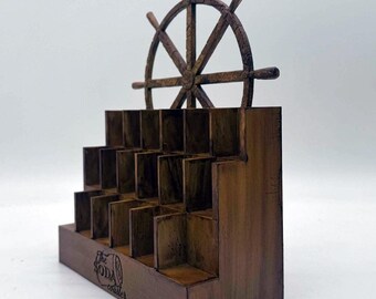 May include: A brown wooden tiered display stand with multiple square compartments for storage. The top features a decorative ship wheel design. The front panel is engraved with the text The Soda Coaster in a circular logo format.