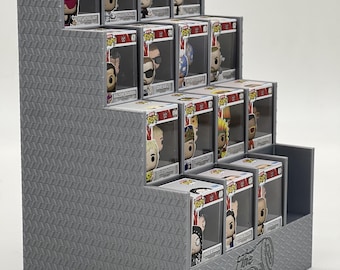 May include: A gray, tiered display stand with a diamond plate texture, designed to hold collectible vinyl figures in their boxes. The front panel features the embossed text "The SOD coaster." The stand has four levels, each holding multiple boxes.
