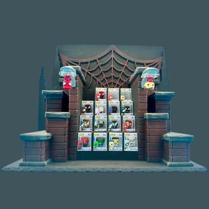 May include: A display stand featuring a brick-patterned structure with a dark spiderweb backdrop. It holds twelve small square boxes containing miniature character figures, with two additional figures perched on top of the side pillars.