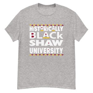 Peut inclure: T-shirt gris avec le texte "Historically Black Shaw University" en lettres blanches avec un motif g&eacute;om&eacute;trique rouge et jaune.