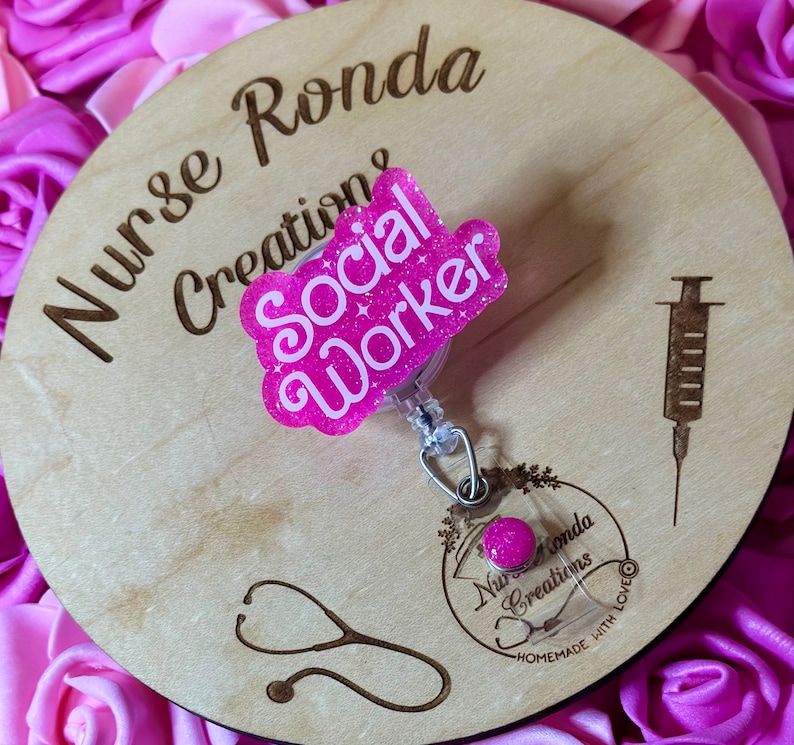 K&ouml;nnte beinhalten: Ein rosa Holz-Kreis mit dem Text "Nurse Ronda Creations" und einem rosa Glitzer-Abzeichen mit der Aufschrift "Social Worker".