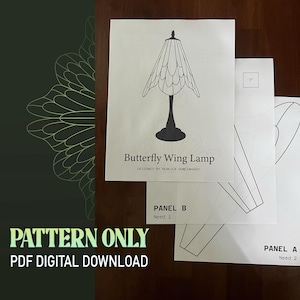 May include: A stack of white paper sheets featuring a butterfly wing lamp design, with the text "Butterfly Wing Lamp" and "Pattern Only PDF Digital Download". Additional sheets show panel diagrams. The design is by Rebecca Gemeinhardt.
