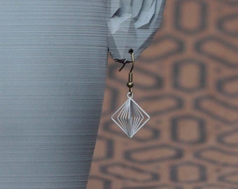 May include: A pair of silver geometric earrings with a dangling design, hanging from a mannequin with pointed ears.