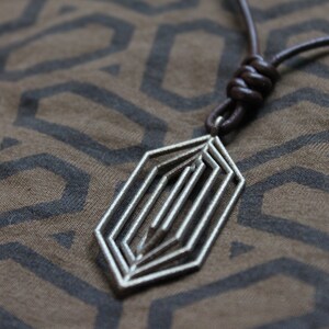 May include: A silver geometric pendant necklace with a brown leather cord. The pendant is a multi-layered, abstract design.