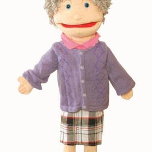 May include: A hand puppet of an elderly woman with gray curly hair, blue eyes, and a red mouth. She wears a purple cardigan, a pink collared shirt, and a plaid skirt. Black shoes complete the outfit. The puppet is designed for entertainment.