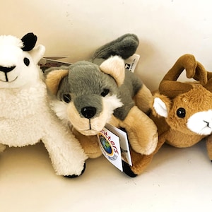 May include: Three plush animal toys: a white llama with black accents, a gray and tan wolf, and a brown deer. Each toy has a tag that reads "Play Critters". The toys are designed for interactive and imaginative play.