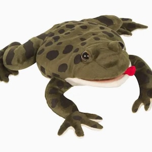 May include: A plush frog toy in shades of green and brown with black spots. The frog has a white mouth, a red tongue, and large, round eyes. Its arms and legs are outstretched, giving it a playful appearance.