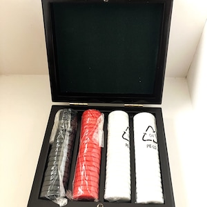 May include: A wooden box with three stacks of poker chips. The chips are black, red, and white. The box has a green felt lining.
