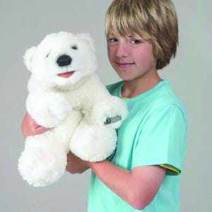 May include: A white plush polar bear puppet with black eyes and a black nose. The puppet is being held by a young person wearing a light blue shirt.