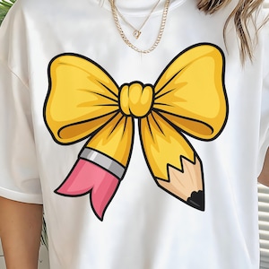 May include: White t-shirt featuring a large yellow bow design with a pencil motif. The bow is outlined in black, and the pencil has a pink eraser and a black tip. The design is centered on the shirt.
