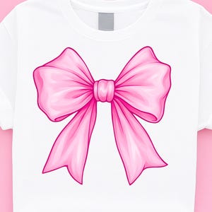 May include: A pink satin bow with a large, centered knot. The bow is on a white t-shirt.