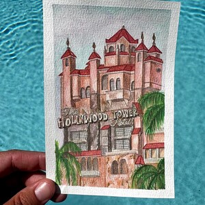May include: Watercolor painting of the Hollywood Tower Hotel, featuring a detailed depiction of the building's architecture. The artwork showcases the hotel's facade with red roofs, palm trees, and the hotel's sign.