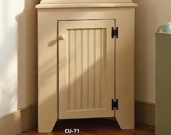 May include: A cream-colored corner hutch and cabinet with a wire mesh door and vertical paneling. A wall shelf with hooks holds a hat and a pink jacket. A framed sign reads "family".