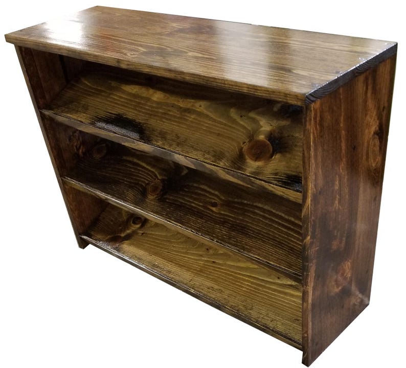 Op de afbeelding: Een donkerbruin houten boekenkast met drie planken. De planken zijn gemaakt van massief hout en hebben een rustieke afwerking.