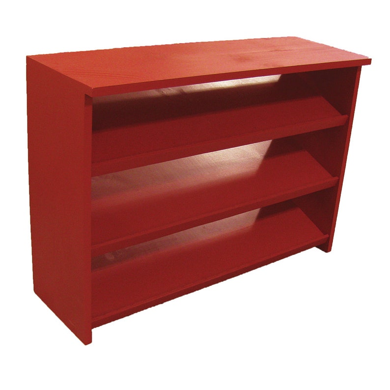 Op de afbeelding: Een rode houten plank met drie planken. De planken zijn licht naar voren gekanteld.