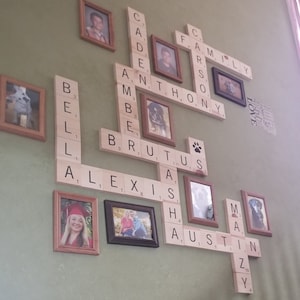 May include: A wall decorated with framed photos and wooden tiles spelling out names, including "Family", "Anthony", "Brutus", "Alexis", and "Austin".