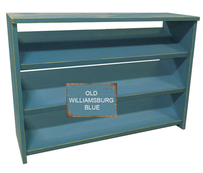 Op de afbeelding: Een blauwe houten plank met drie planken. De planken zijn schuin en hebben een gele rand. De plank is geverfd in een tint genaamd "Old Williamsburg Blue".