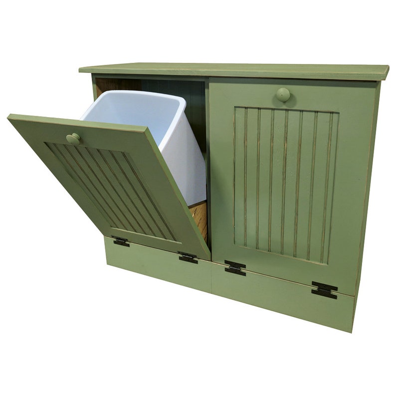 May include: A green wooden double-door trash can with a white plastic bin inside. The left door is open, revealing the bin. The trash can has a simple design with vertical slats on the doors.