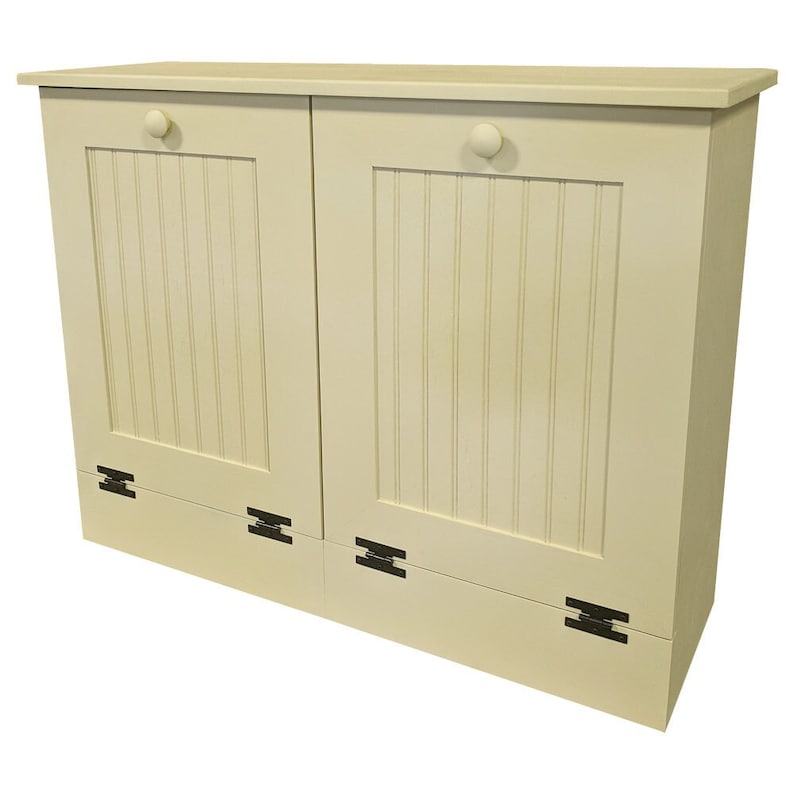 May include: A white wooden double-door trash can with a pull-out drawer. The doors have a simple knob and vertical paneling. The drawer has black metal hinges.