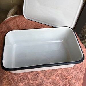 May include: White enamelware baking dish with a black rim. The dish has a lid and is in good condition.