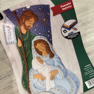 Könnte beinhalten: Ein Filzstrumpf-Set mit einer Weihnachtsgeschichte mit Maria, Josef und dem Jesuskind. Das Set enthält gestanzten Filz, Pailletten, Perlen und Anleitungen. Der Strumpf ist 45,7 cm lang.
