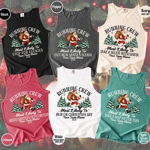 May include: Six sleeveless tank tops in black, pepper, ivory, crimson, white, and light green. Each features a graphic of Santa Claus running with a sack, pine trees, and the text RUNNING CREW, 2026, and unique phrases like MOST LIKELY TO STOP FOR COOKIES.