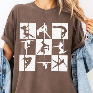 Könnte beinhalten: Ein dunkelbraunes T-Shirt mit einem Raster aus neun weißen Quadraten, die jeweils die Silhouette einer Person bei einer anderen Pole-Dance-Figur zeigen. Das Wort Espresso ist in schwarzer Schreibschrift oben links abgebildet.