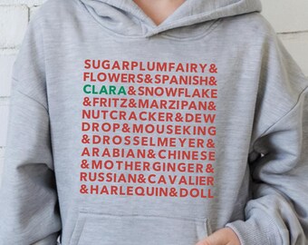 May include: A light gray hoodie with a front pocket and a hood. The hoodie features a list of text in red and green, including "SUGARPLUMFAIRY" and "CLARA". The words are stacked vertically.