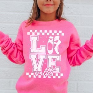 May include: A pink sweatshirt with a white graphic that says "LOVE ballet" with a pair of ballet shoes in the "O".