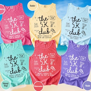 May include: Six sleeveless tank tops in crunchberry, butter, chambray, island reef, watermelon, and violet colors. Each features the text 'the 5K club', 'Est. 2026', 'Portland, OR', and unique phrases like 'most likely to run on coffee' with 5K icons.