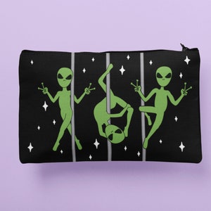 May include: Black zippered pouch featuring a graphic of three green aliens dancing on poles against a black background with white stars.
