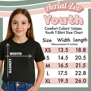 May include: A black t-shirt size chart titled Aerial Zoo Youth Comfort Colors Unisex Youth T-Shirt Size Chart. The chart lists sizes XS through XL with corresponding width and length measurements in inches, illustrated with a diagram on the shirt.
