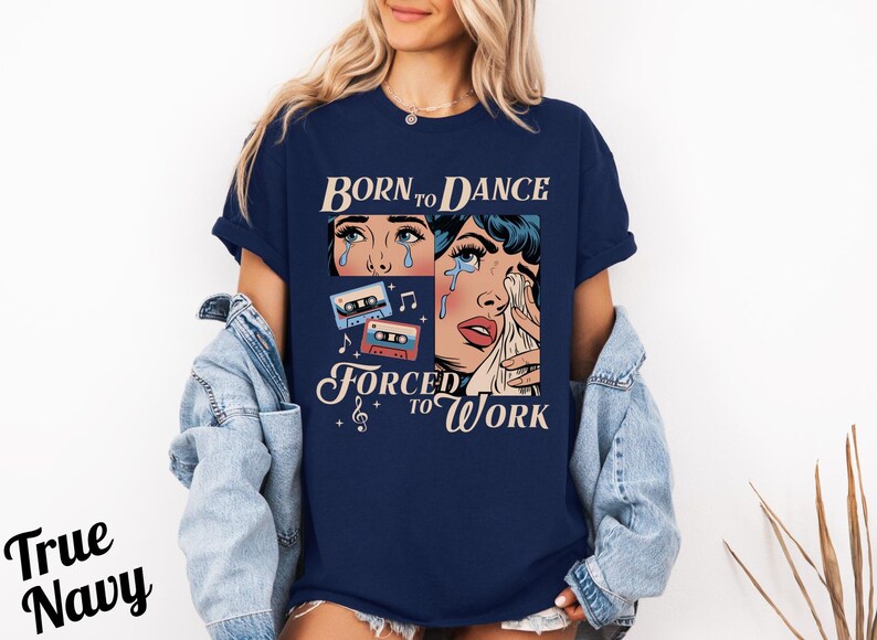 May include: A navy blue t-shirt with a graphic of a woman with tears in her eyes and the text "Born to Dance Forced to Work". The graphic also includes cassette tapes and musical notes.