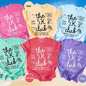 May include: A collection of six short-sleeved t-shirts in crunchberry pink, butter yellow, chambray blue, island reef green, watermelon red, and violet. Each shirt features black or white text reading the 5K club, Est. 2026, Portland, OR, and unique phrases.
