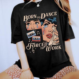 May include: Black t-shirt with a retro comic book style graphic of a woman crying with the text "Born to Dance Forced to Work" and cassette tapes.