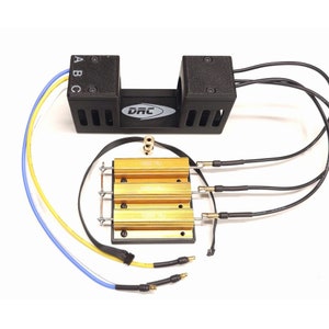 May include: An electronic device with a black housing and gold-colored components. The device has multiple wires with connectors and the text "100W 18J". The device also has the letters "A", "B", and "C" on the housing.