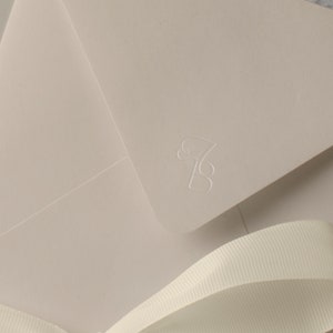 May include: A light beige envelope with a white ribbon and the number "7B" embossed in the upper right corner.