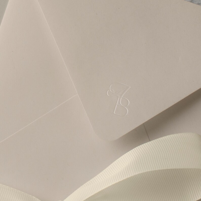 May include: A light beige envelope with a white ribbon and the number "7B" embossed in the upper right corner.