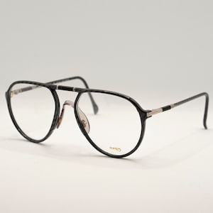 May include: Black aviator-style eyeglasses with a silver accent on the bridge and arms. The brand name "FLURS" is printed on the right arm.