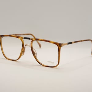 May include: Eyeglasses with a tortoiseshell pattern frame and clear lenses. The glasses have a rectangular shape with a double bridge and thin metal arms. The brand name "FLEXUS" is visible on the lower right lens.