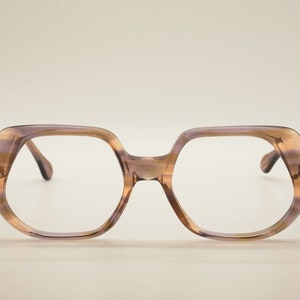 May include: A pair of brown and purple square-shaped eyeglasses with clear lenses.
