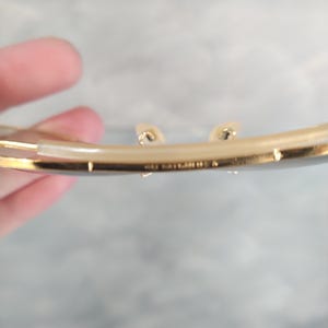 May include: Close-up of the underside of a gold-toned pair of glasses with the text "Made in Italy" engraved on the metal.
