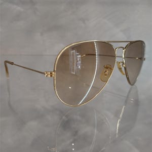Puede incluir: Gafas de sol aviador doradas con lentes de degradado marr&oacute;n. Las gafas tienen un dise&ntilde;o cl&aacute;sico y est&aacute;n en buen estado.
