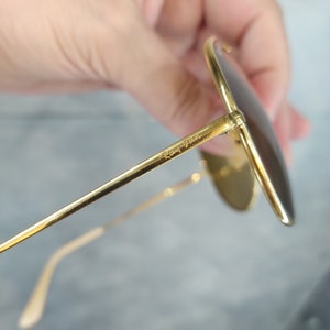 May include: Gold-tone aviator sunglasses with a Ray-Ban logo on the arm.