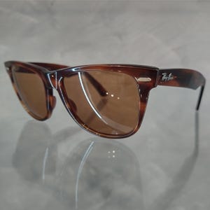May include: Brown tortoise shell sunglasses with brown lenses. The sunglasses have a Ray-Ban logo on the right temple.