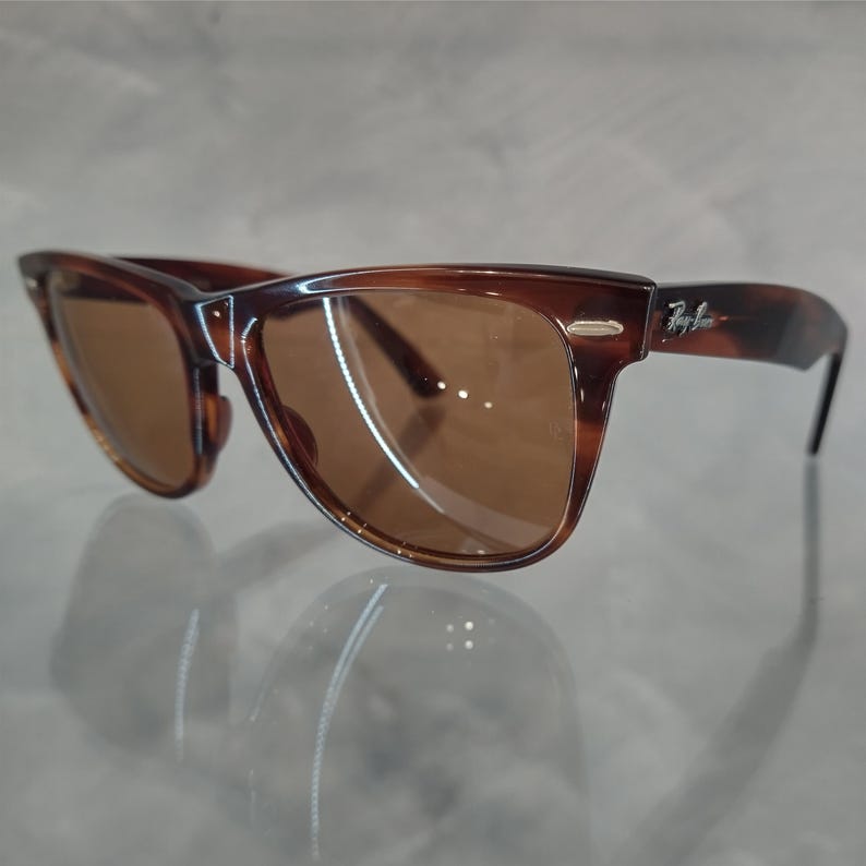 May include: Brown tortoise shell sunglasses with brown lenses. The sunglasses have a Ray-Ban logo on the right temple.