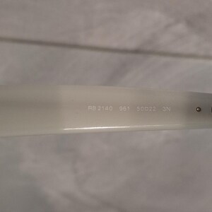Pu&ograve; includere: Primo piano del braccio di un paio di occhiali da sole bianco sporco. Il testo "RB 2140 961 50▢22 3N" &egrave; stampato sul braccio. Gli occhiali da sole sono di stile classico.