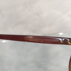 May include: Close-up of the brown plastic frame of a pair of glasses. The text "FRAME FRANCE NYLON" is visible on the frame.