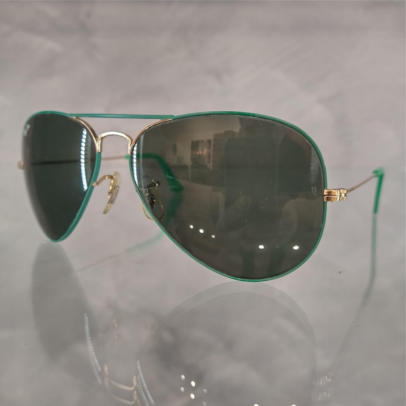 Op de afbeelding: Groene aviator zonnebril met gouden montuur en gespiegelde glazen.