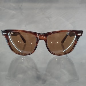 May include: Brown tortoise shell Ray-Ban Wayfarer sunglasses with brown lenses.